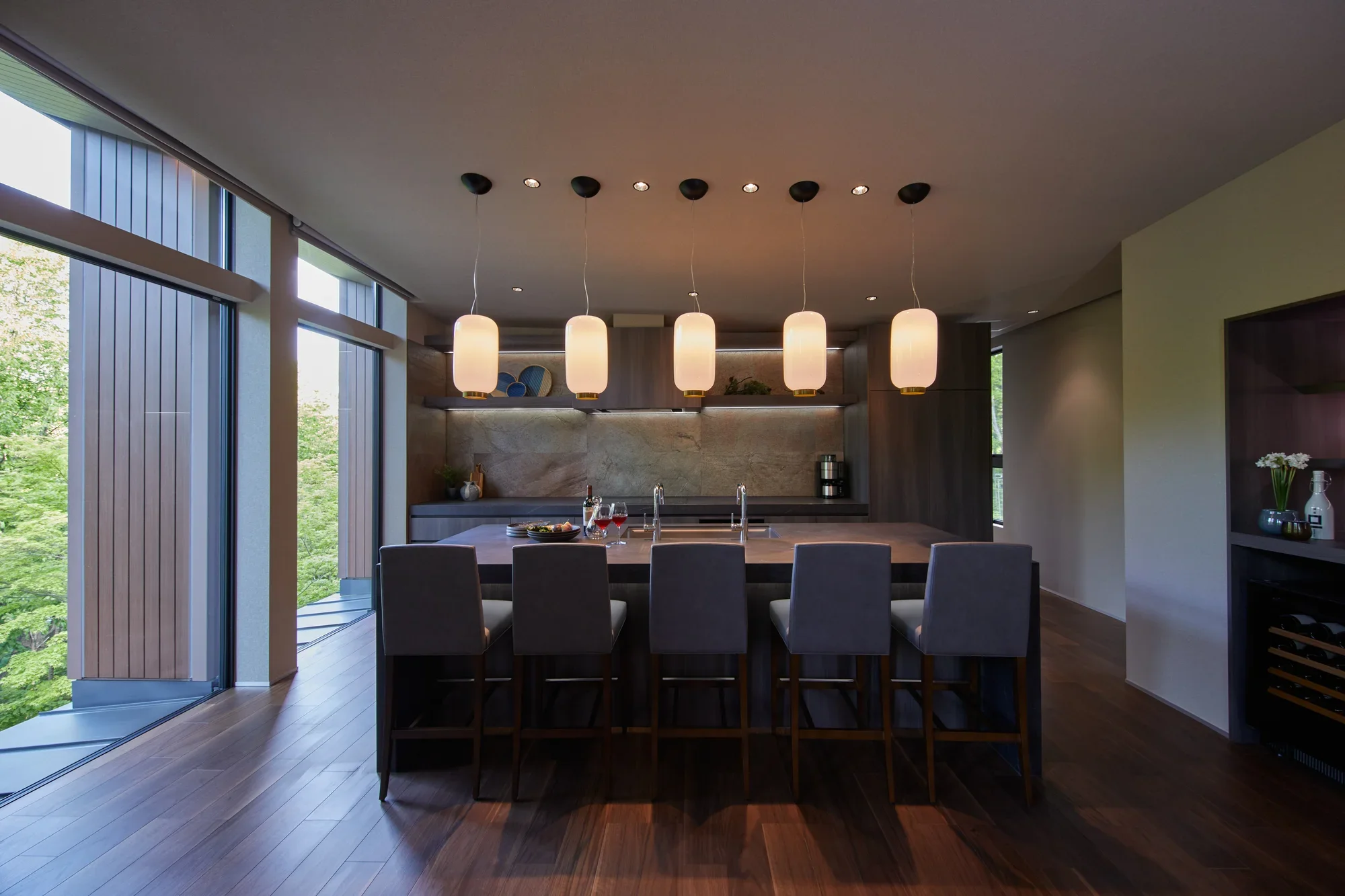 A kitchen counter with stools and pendant lights