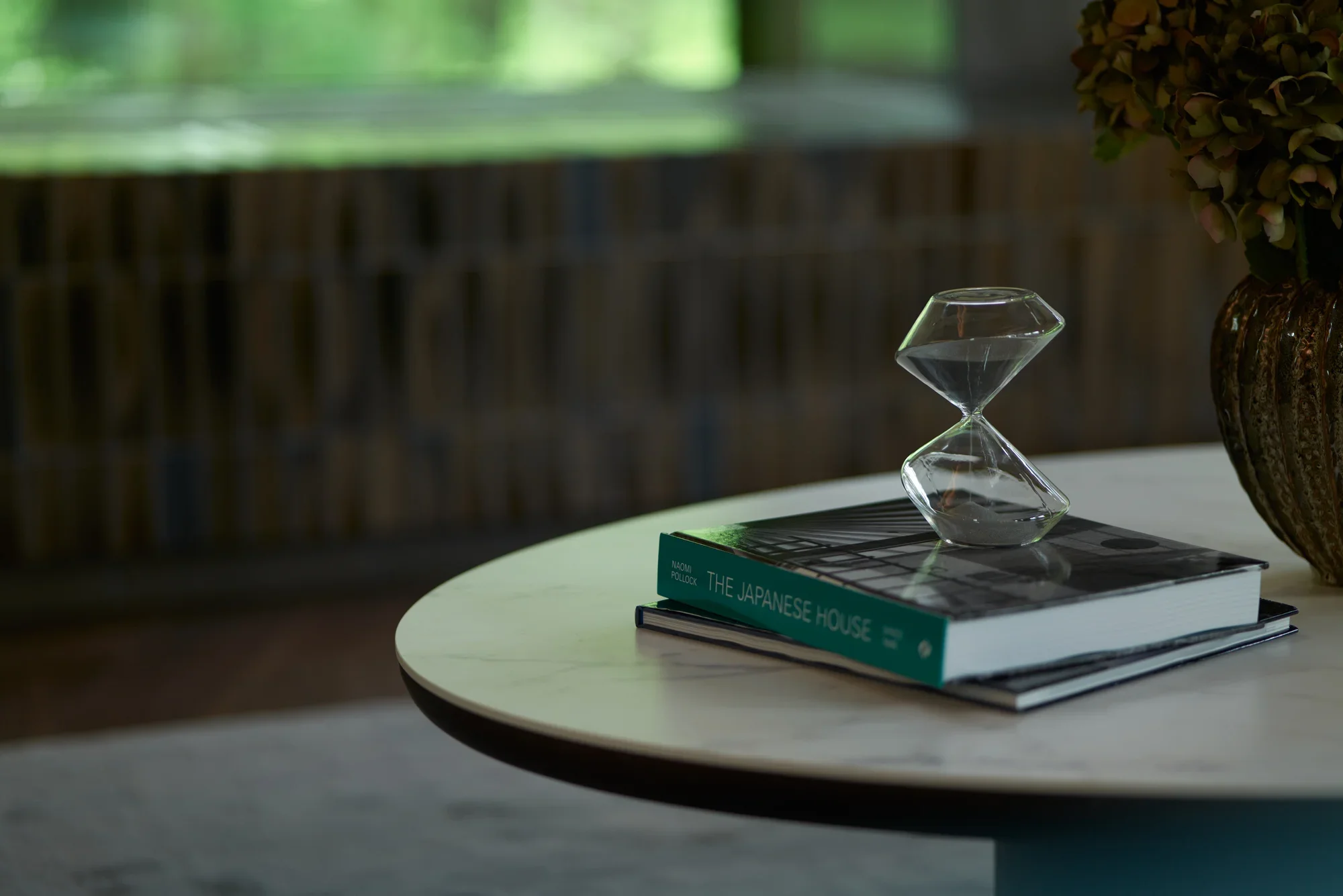 An hourglass resting on books on a round table