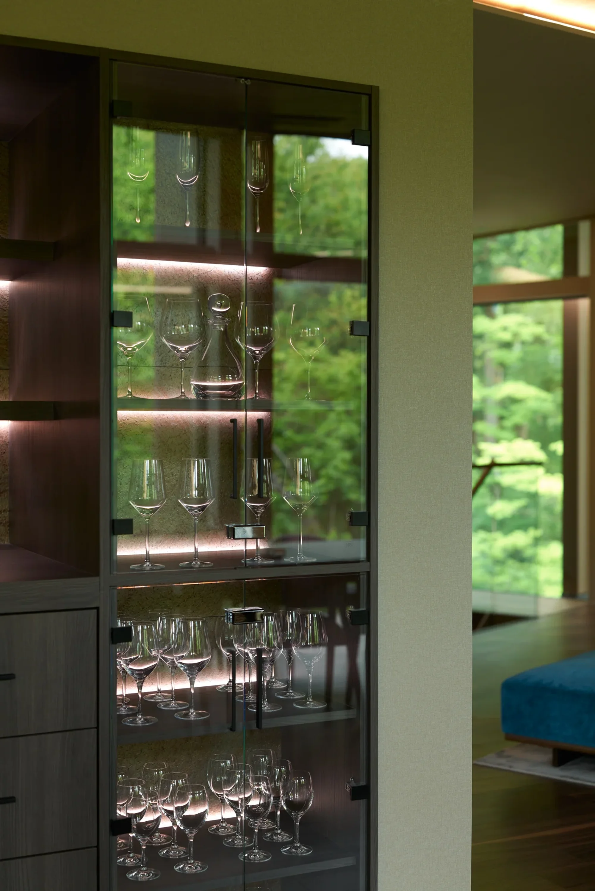 Glassware in a lit cabinet beside a window