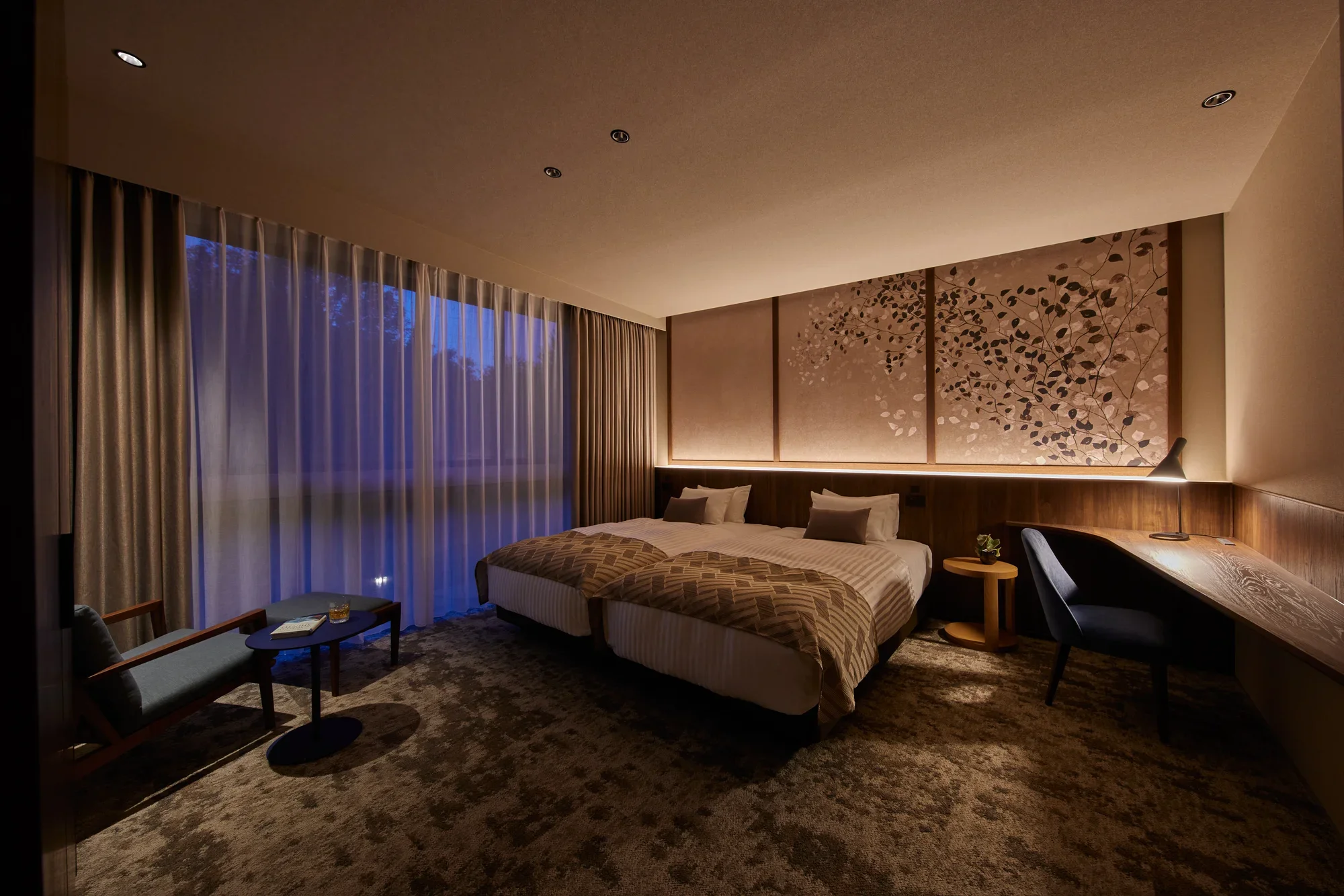 Two beds beside curtained windows and patterned wall panels