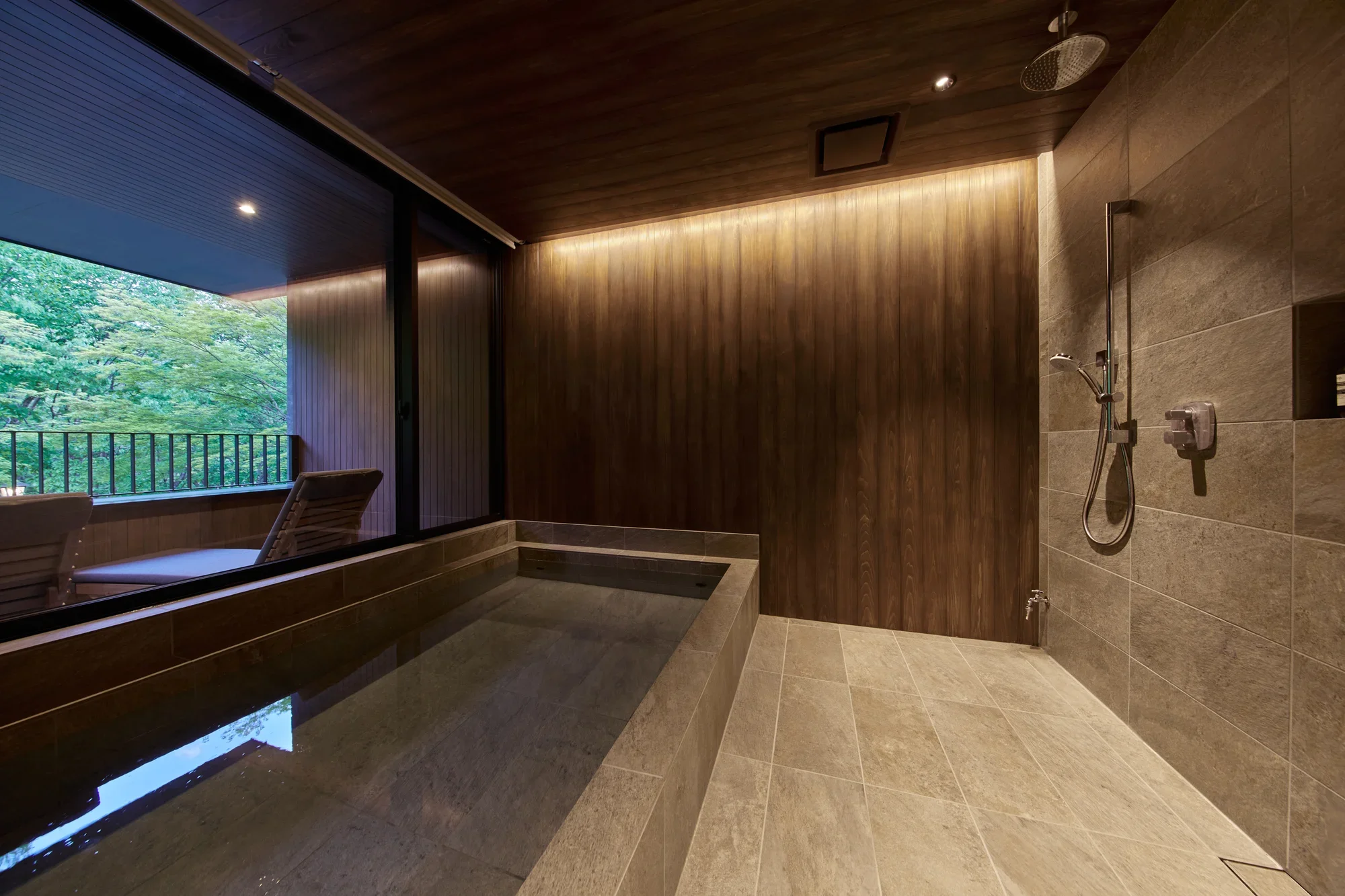 A bath and shower with forest beyond the window