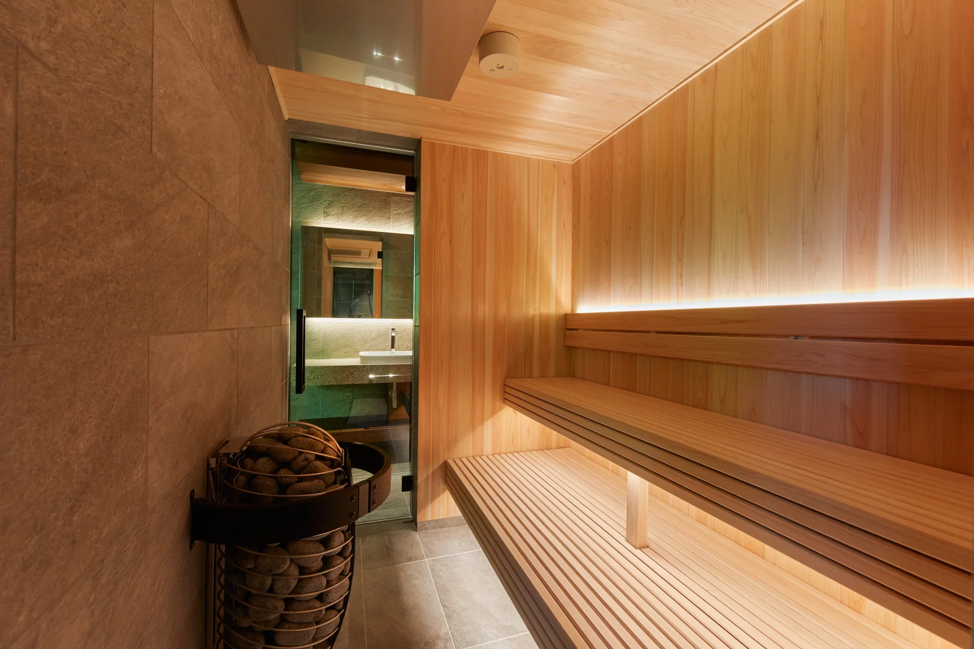 Wooden sauna benches beside a stone heater